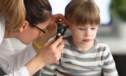Ärztin untersucht das Ohr eines Kindes