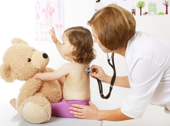 Ärztin horcht ein Kind mit einem Stethoskop ab