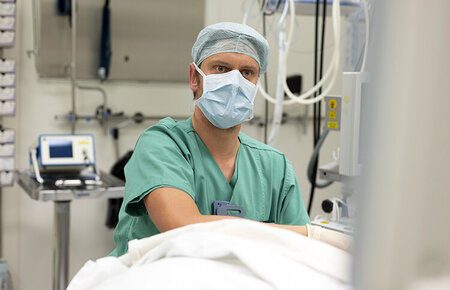 Anästhesist im OP-Saal, der auf einen Monitor schaut.