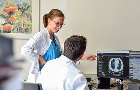 Eine Ärztin und ein Arzt besprechen am Computer eine radiologische Aufnahme