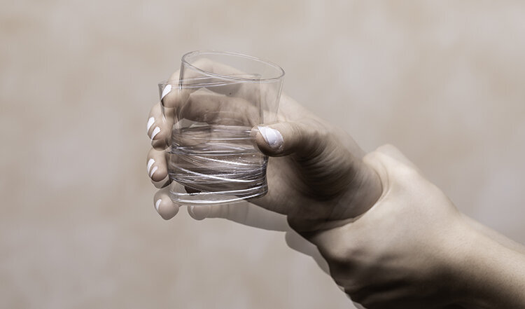 Symbolbild für die Erkrankung Morbus Parkinson: ein Glas in einer zitternden Hand.
