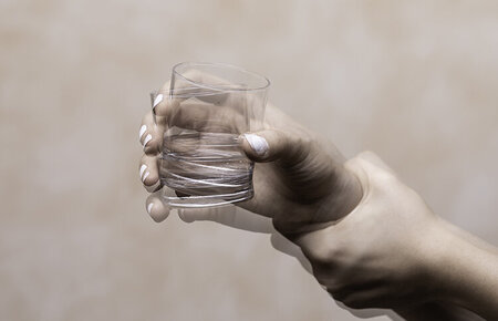 Symbolbild für die Erkrankung Morbus Parkinson: ein Glas in einer zitternden Hand.