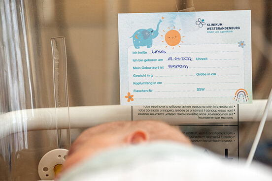 Frühchen Linus schlafend in seinem Bettchen, im Hintergrund eine Karte mit seinem Namen und dem Geburtsdatum