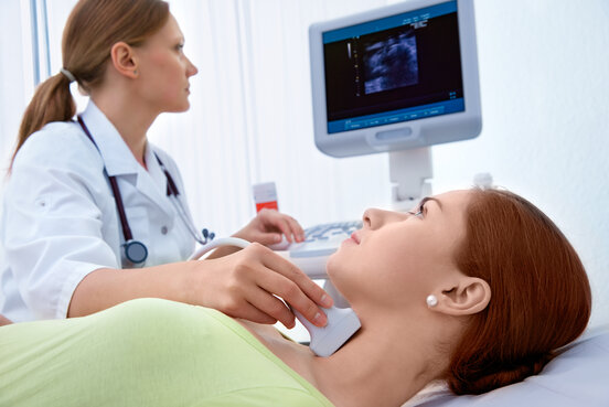 Ärztin führt bei einer Patientin eine Ultraschalluntersuchung der Schilddrüse durch.