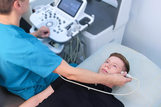Arzt am Ultraschallgerät, führt eine neurologische Untersuchung an der Schläfe durch