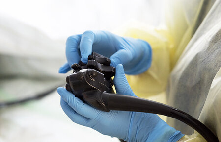 Großaufnahme von Händen mit blauen Handschuhen, die ein Endoskop bedienen
