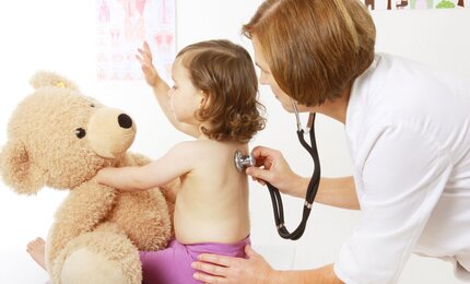 Ärztin horcht ein Kind mit einem Stethoskop ab