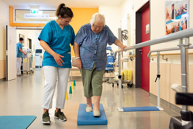 Physiotherapeutin unterstützt eine Patientin beim Gleichgewichtstraining