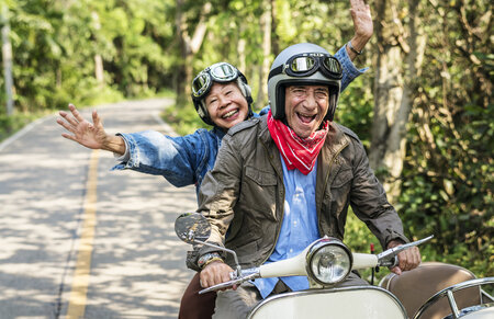Zwei Senioren fahren auf einem Motorroller
