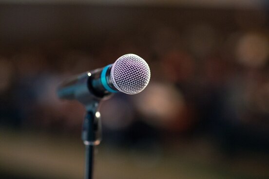 Ein alleinstehendes Mikrophone vor Publikum