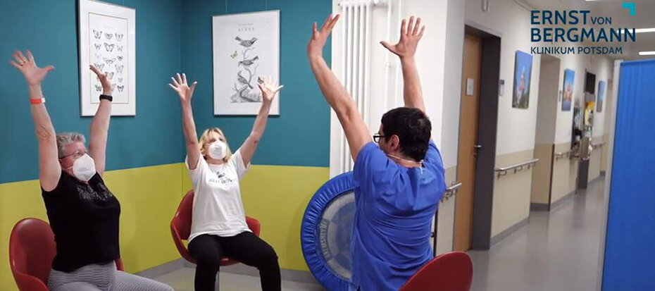 Physiotherapeut leitet zwei Patientinnen bei einer sportlichen Übung an.